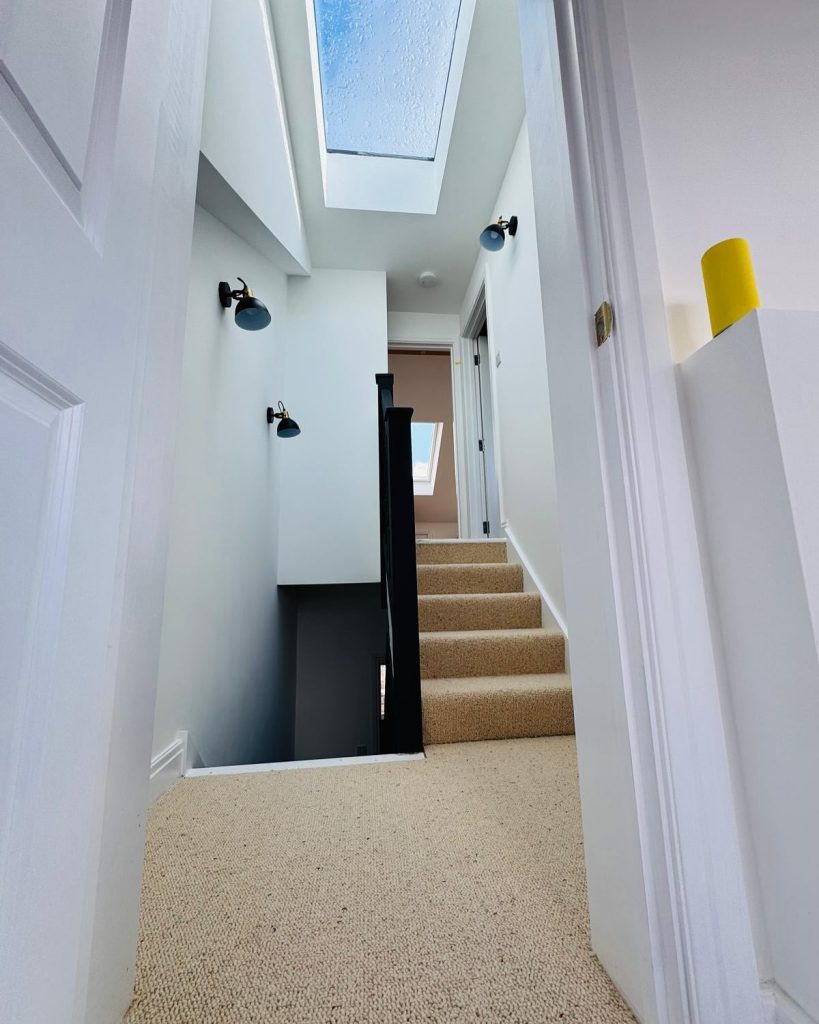 Bright loft conversion hallway with skylight, new staircase, and modern wall lights completed by J2 Build.